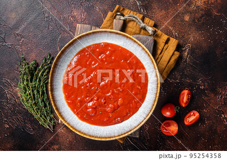 Homemade tomato Passata in rustic plate with herbs. Dark background. Top view 95254358