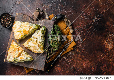 Spanakopita Greek Pie with Spinach and Cheese on wooden board. Dark background. Top view. Copy space Spanakopita Greek Pie with Spinach and Cheese on wooden board. Dark background. Top view. Copy space 95254367