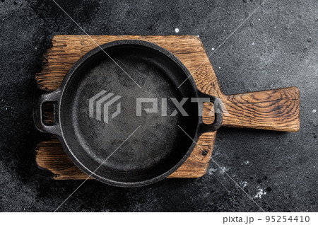 Cooking background with Empty cast-iron skillet on rustic towel. Black background. Top view. Copy space Cooking background with Empty cast-iron skillet on rustic towel. Black background. Top view. Copy space 95254410