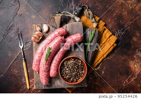 Bratwurst Raw meat sausages on wooden board with spices. Dark background. Top view 95254426