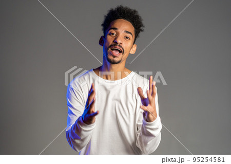 Young energetic african american man in white wear smiling and dancing in good mood on brown 95254581
