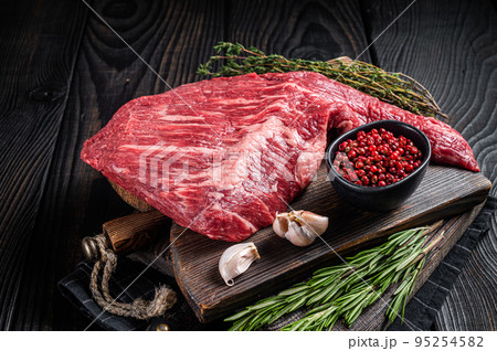 Tri Tip black angus beef steak on cutting board with herbs, raw meat. Black Wooden background. Top view 95254582