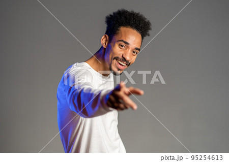 Young energetic african american man in white wear smiling and dancing in good mood on brown Young energetic african american man in white wear smiling and dancing in good mood on brown 95254613