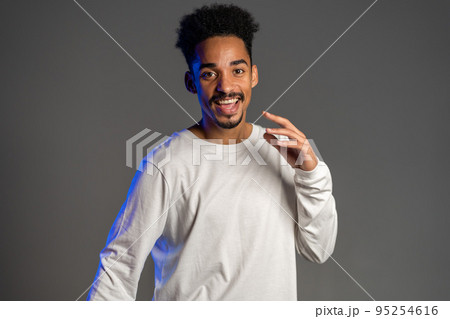 Young energetic african american man in white wear smiling and dancing in good mood on brown 95254616