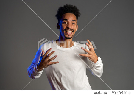 Young energetic african american man in white wear smiling and dancing in good mood on brown 95254619