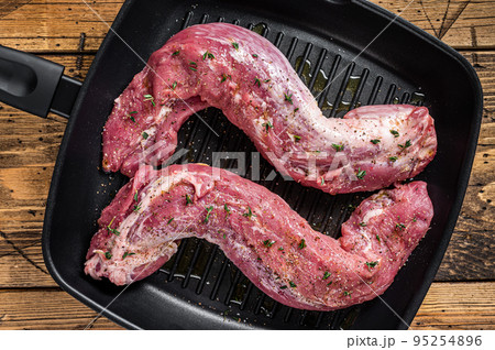 Raw Tenderloin pork fillet ready for cooking, uncooked meat in grill pan with herbs and olive oil. Wooden background. Top view Raw Tenderloin pork fillet ready for cooking, uncooked meat in grill pan with herbs and olive oil. Wooden background. Top view 95254896