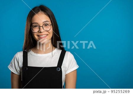 Pretty young asian girl with long hair standing on blue studio background. Cute portrait of woman in 95255269