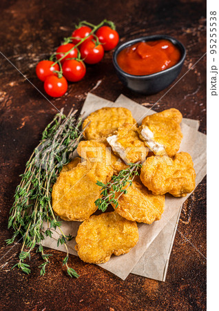 Pile of crispy homemade baked chicken nuggets with ketchup. Dark background. Top view Pile of crispy homemade baked chicken nuggets with ketchup. Dark background. Top view 95255538