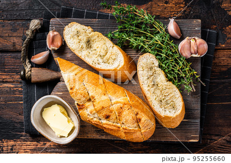 Toasted Garlic bread with herbs and butter on wooden cutting board. Wooden background. Top view Toasted Garlic bread with herbs and butter on wooden cutting board. Wooden background. Top view 95255660