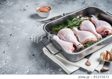 Raw organic chicken legs, drumsticks in kitchen tray with herbs. Gray background. Top view. Copy space Raw organic chicken legs, drumsticks in kitchen tray with herbs. Gray background. Top view. Copy space 95255672