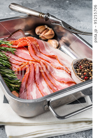 Raw smoked bacon slices with rosemary and garlic. Gray background. Top view Raw smoked bacon slices with rosemary and garlic. Gray background. Top view 95255706