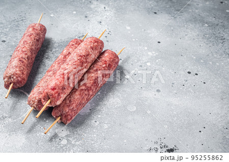 Raw kofta or lula kebabs skewers on butcher board. Gray background. Top view. Copy space 95255862