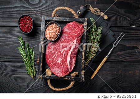 Unccoked rump steak or raw top sirloin beef meat steak. Black wooden background. Top view Unccoked rump steak or raw top sirloin beef meat steak. Black wooden background. Top view 95255951