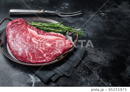 Raw top sirloin beef meat steak in a steel tray with rosemary. Black background. Top view. Copy space Raw top sirloin beef meat steak in a steel tray with rosemary. Black background. Top view. Copy space 95255973
