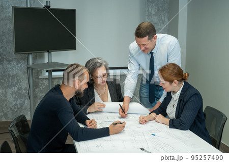 The boss gives instructions to three employees in the office conference room. Brainstorming engineers and architects.  95257490