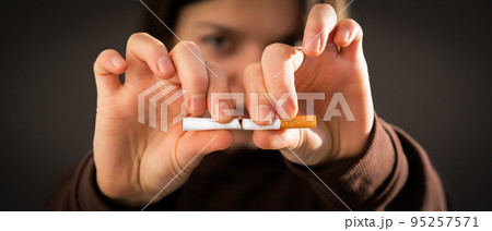 Girl breaks a cigarette in her hands, view closeup. 95257571