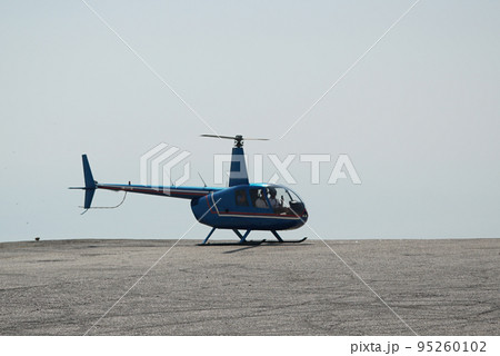 Blue helicopter flying in grey cloudy skies Blue helicopter flying in grey cloudy skies 95260102