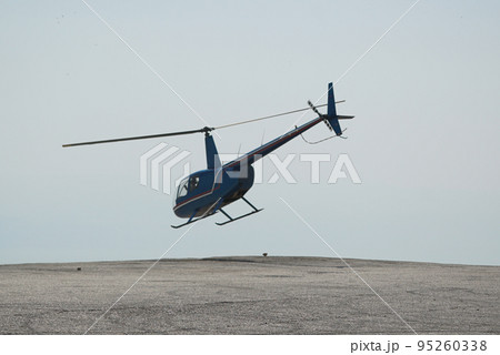 Blue helicopter flying in grey cloudy skies Blue helicopter flying in grey cloudy skies 95260338