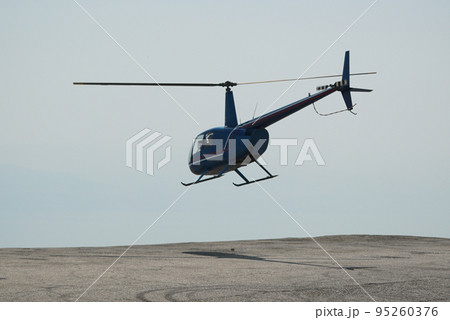 Blue helicopter flying in grey cloudy skies Blue helicopter flying in grey cloudy skies 95260376