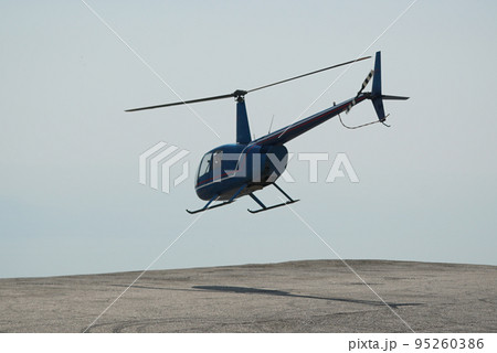 Blue helicopter flying in grey cloudy skies Blue helicopter flying in grey cloudy skies 95260386