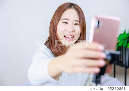 セルカ棒についた携帯電話を操作する女性 セルカ棒についた携帯電話を操作する女性 95260868