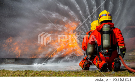 Asian firefighter on duty firefighting, Asian fireman spraying high pressure water, Fireman in fire fighting equipment uniform spray water from hose for fire fighting. Asian firefighter on duty firefighting, Asian fireman spraying high pressure water, Fireman in fire fighting equipment uniform spray water from hose for fire fighting. 95262813