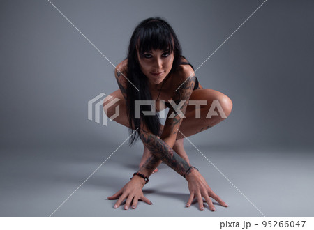 Photo of the nude brunette girl with tattoo sitting on the floor 95266047