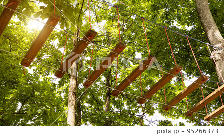 Rope town on the background of trees. Entertainment in the park for children and adults. 95266373