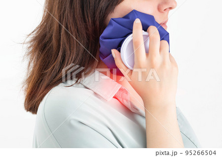 A girl attaches a medical bag with cold to the swelling on her cheek after removing a wisdom tooth. Concept for pain relief and inflammation in dentistry with the help of cold 95266504