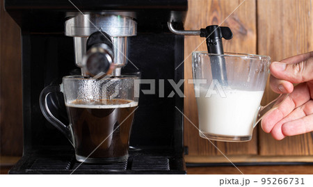 Foaming and heating milk with steam in a manual cappuccinatore machine in the kitchen. Close-up 95266731