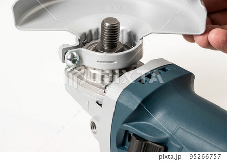 Installing the safety cover on an angle grinder, close-up. Safety precautions when working with construction power tools. Installing the safety cover on an angle grinder, close-up. Safety precautions when working with construction power tools. 95266757