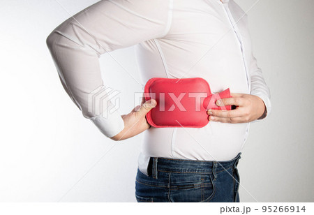 A man holds a red heating pad with water near the side of his back. The concept of treatment of sprains, hypothermia of muscles and ligaments. Thermotherapy 95266914