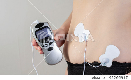 A modern electronic acupuncture for burning belly fat and strengthening muscles on the girl's body, close-up 95266917