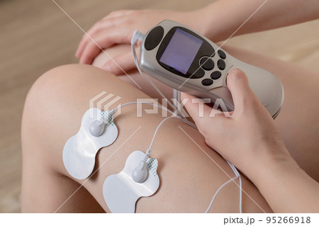 Electrodes of modern acupuncture and anti-cellulite massagers on the legs of a girl in problem areas. Home physiotherapy, close-up 95266918