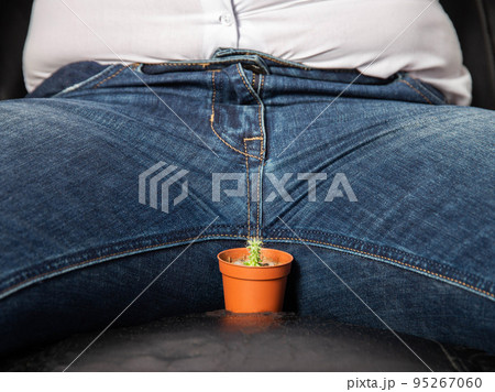 A man sits on a chair near the groin is a small cactus. The concept of male problems, a small penis, hormones and dysfunction in the genital area. Circumcision 95267060