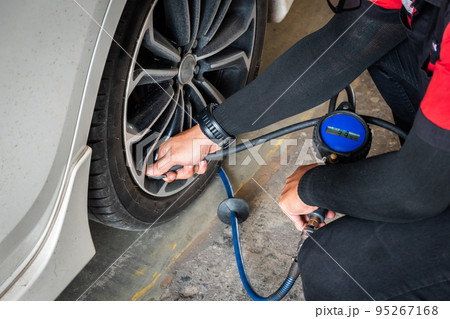 Expert mechanic checks tire pressure with nitrogen and has a pressure gauge. 95267168