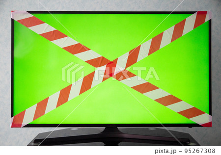 Green TV screen with red and white prohibition tape. The concept of a sanction on television, a ban on broadcasting TV shows. Technology Green TV screen with red and white prohibition tape. The concept of a sanction on television, a ban on broadcasting TV shows. Technology 95267308
