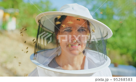 Bees flying around the face of a beekeeper 95268583