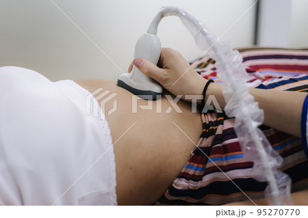 Doctor giving patient an ultrasound. Young woman getting pancreas control in moder clinic 95270770