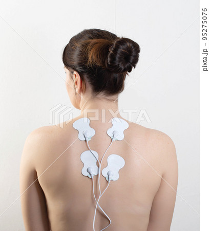 Acupuncture electronic massager on the girl's back to relax muscles and relieve back pain. Home physiotherapy Acupuncture electronic massager on the girl's back to relax muscles and relieve back pain. Home physiotherapy 95275076