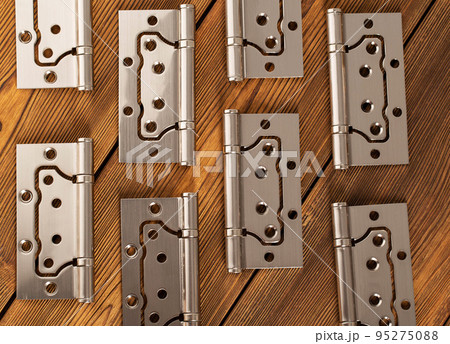 door metal hinges on a wooden background, macro. Door furniture door metal hinges on a wooden background, macro. Door furniture 95275088