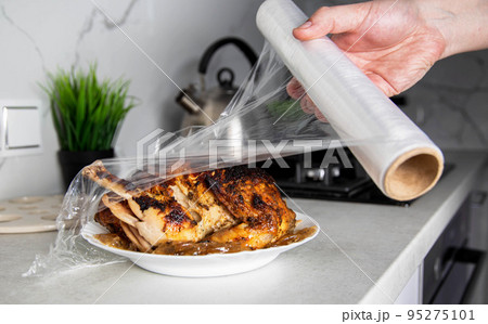 A man wraps a fried chicken in cling film to keep it fresh and smelly. Close-up A man wraps a fried chicken in cling film to keep it fresh and smelly. Close-up 95275101