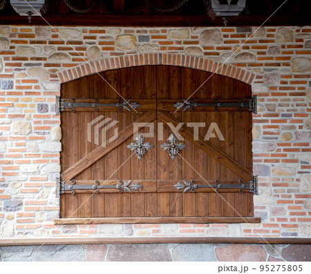 Semicircular wooden gate with wrought door handles and wrought door hinges. Ancient beautiful brick building, architecture, traditional 95275805