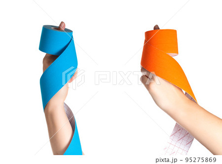 The girl holds in her hands a kinesiological tape of blue and orange color on a white background, isolate. Close-up 95275869