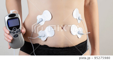 A modern electronic acupuncture for burning belly fat and strengthening muscles on the girl's body, close-up 95275980