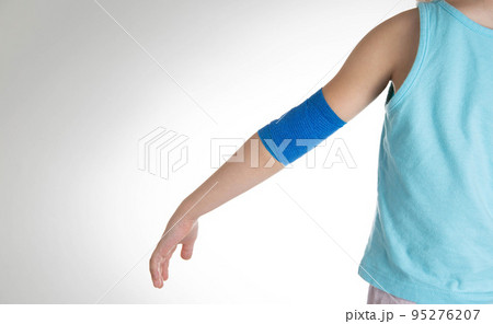 Blue elastic bandage on the elbow joint of the child on the arm. White background, close-up. Hand pain 95276207