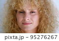 Confident portrait of an attractive charming curly redhead young woman with fresh and radiant skin smiling sweetly looking at the camera. Beautiful diverse people, femininity, human face. Headshot 95276267
