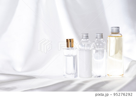 白いサテン生地に並べたガラスとプラスチック化粧品ボトル4個 95276292