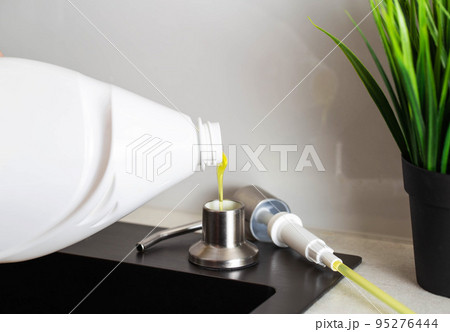 Dismantled detergent dispenser built into the sink. Adding soap to the dispenser. Copy space for text 95276444