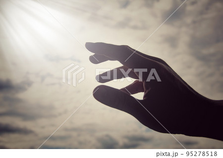 Hand reaching out to bright shining light on sky above. Religious and spiritual concept Hand reaching out to bright shining light on sky above. Religious and spiritual concept 95278518